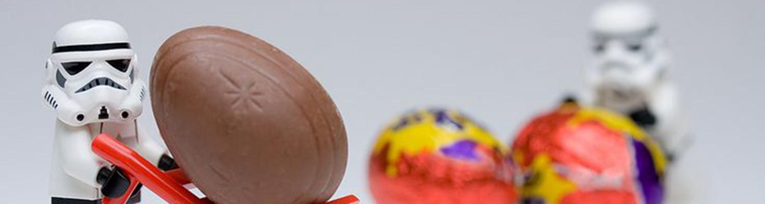 A LEGO Stormtrooper pushing around Cadbury eggs against a white background.