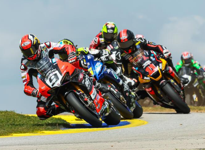 A line of MotoAmerica Superbikes racing together.