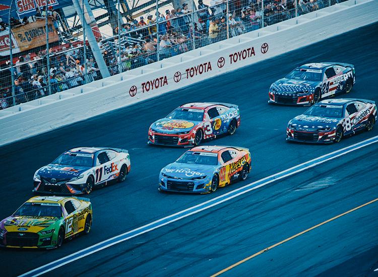 A pack of racecars on the high banks of Charlotte Motor Speedway during the 2022 Coca-Cola 600.